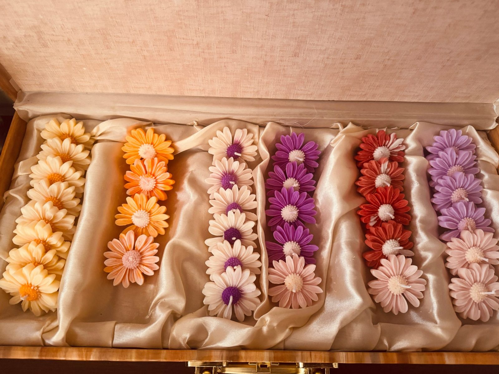 Reejh handcrafted daisy candles in cream, orange, white-purple, purple, red and lilac, arranged in rows