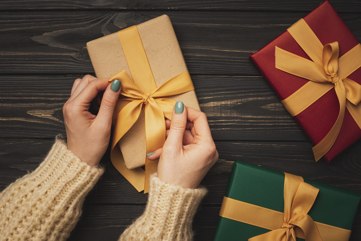 Hands tying a golden ribbon on a gift